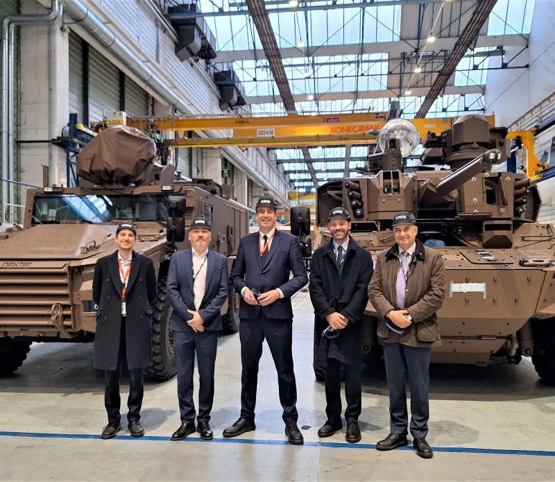 Olivier Becht en visite sur le site KNDS de Roanne, devant des véhicules blindés