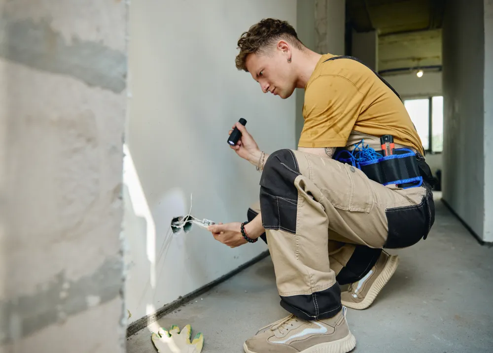 Un artisan électricien au travail sur un chantier de rénovation